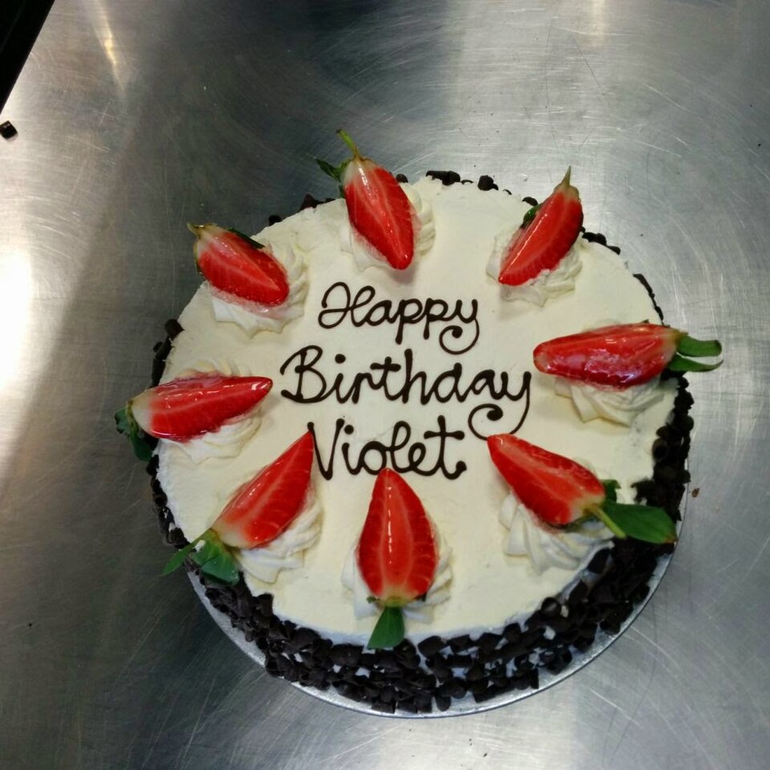 A celebration cake decorated with cream and strawberries, made to order at Baker Street Bakery